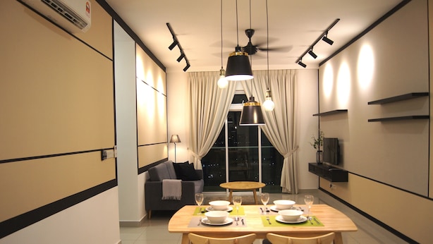 A modern dining area with a wooden table set for four, a sofa, and a TV in the background. - Twin Galaxy Suites (Johor Bahru)