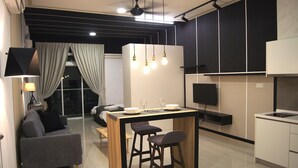 A modern kitchen with a dining area, a sofa, and a TV. - Twin Galaxy Suites (Johor Bahru)