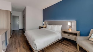 A modern hotel room with a large bed, bedside tables, a chair, and a blue accent wall. - Comfort Inn (Thomasville)