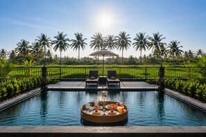 A pool with a floating tray of breakfast items, surrounded by palm trees and a clear sky. - Griya Private Villa (Ubud)