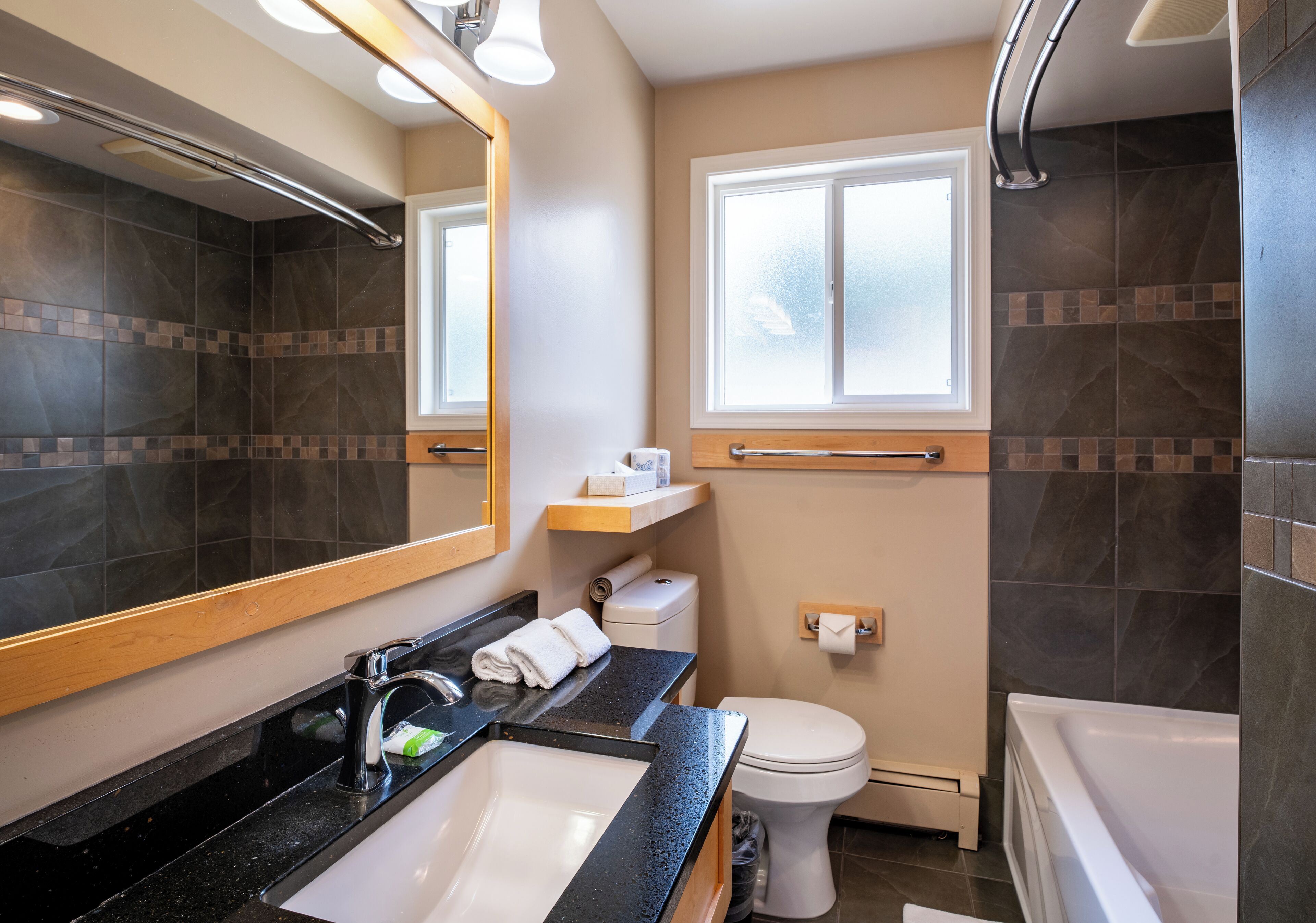 Un baño moderno con un espejo grande, un lavabo, un inodoro y una bañera.