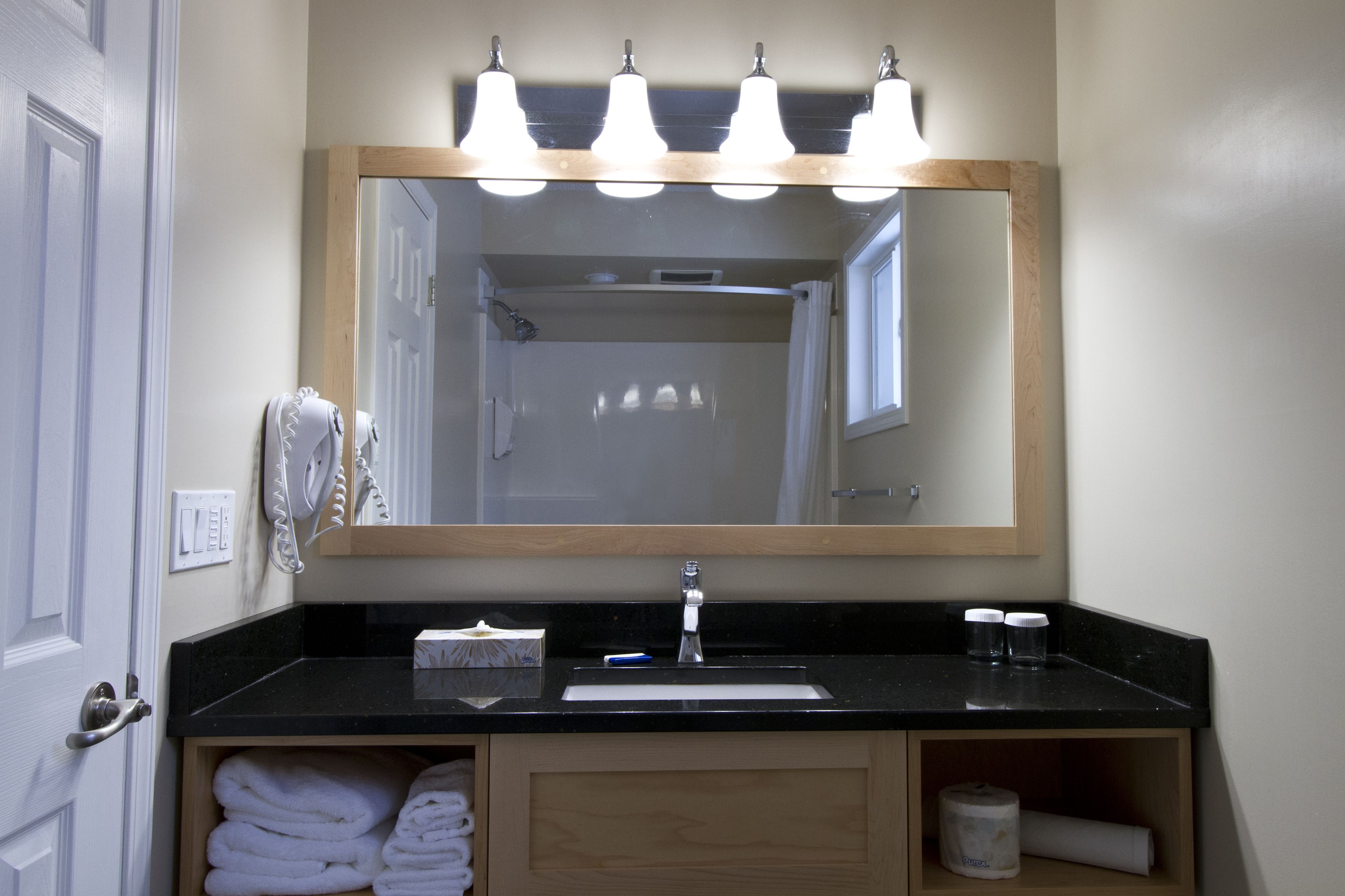 A bathroom with a black countertop, a mirror, a sink, and a towel rack.