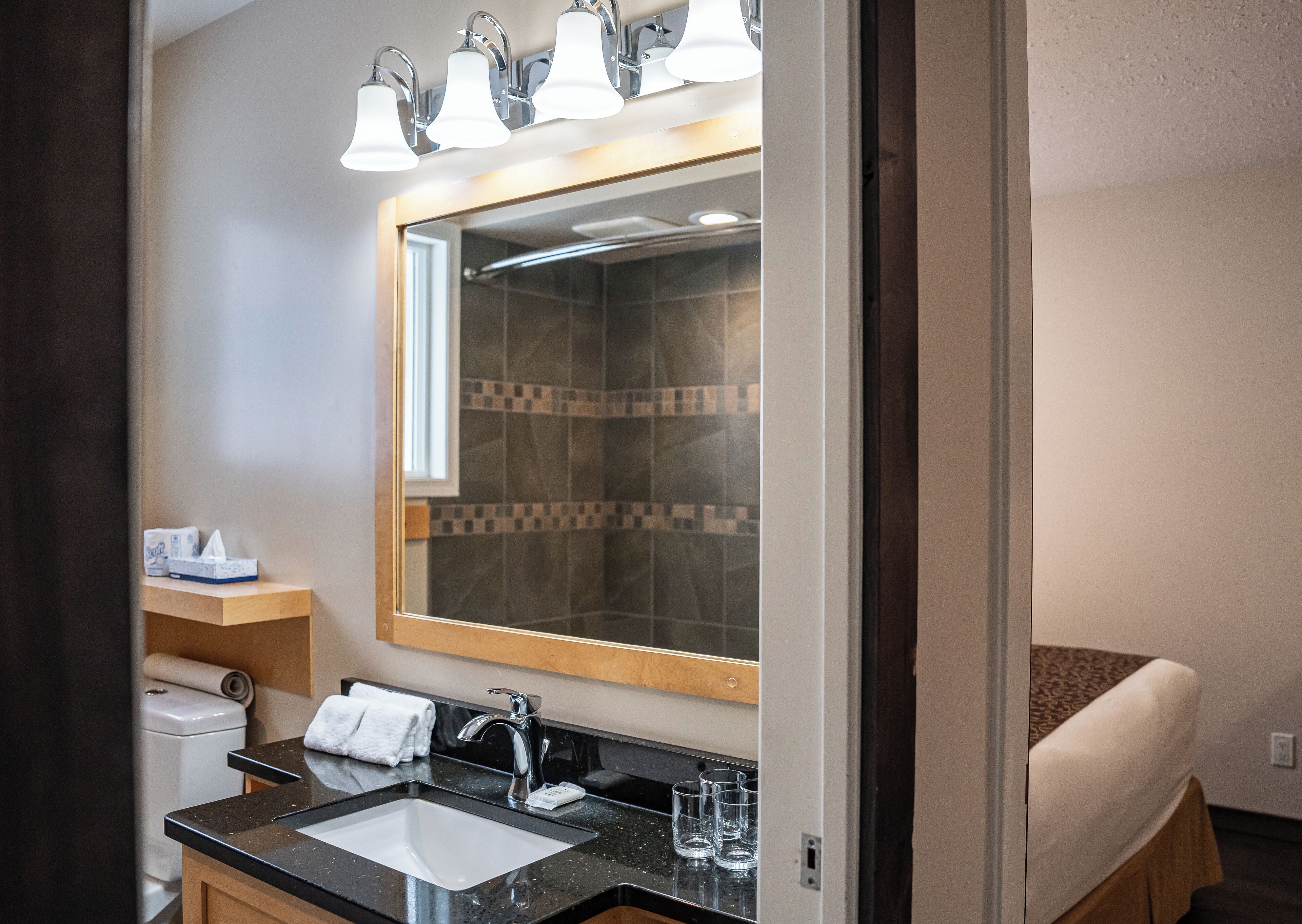 A modern bathroom with a large mirror, a sink, and a shower.