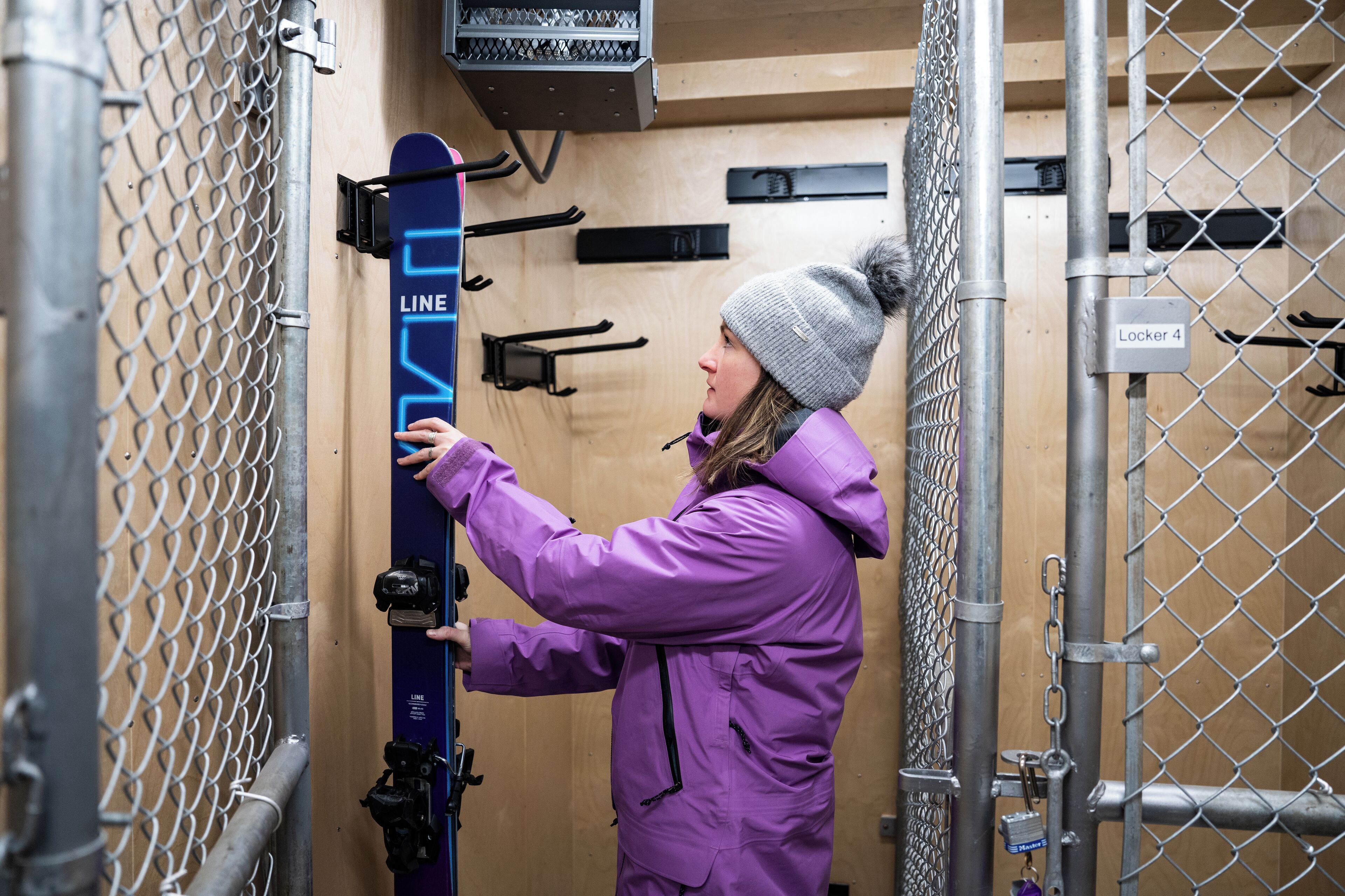 A person in a purple coat interacting with a ski lift.
