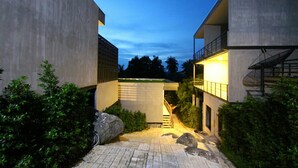 A modern building with a concrete facade, a central staircase, and a small garden area with rocks and shrubs. - Matina Mountain Resort (Koh Tao)