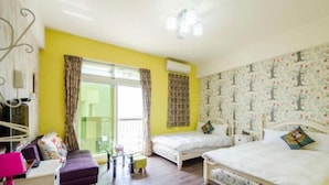 Una habitación con dos camas, un sofá, una mesita y una ventana con cortinas.