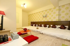 A hotel room with two beds, a desk with a lamp, a small table, and a red bench. - Flower 4 B&B (Hualien City)