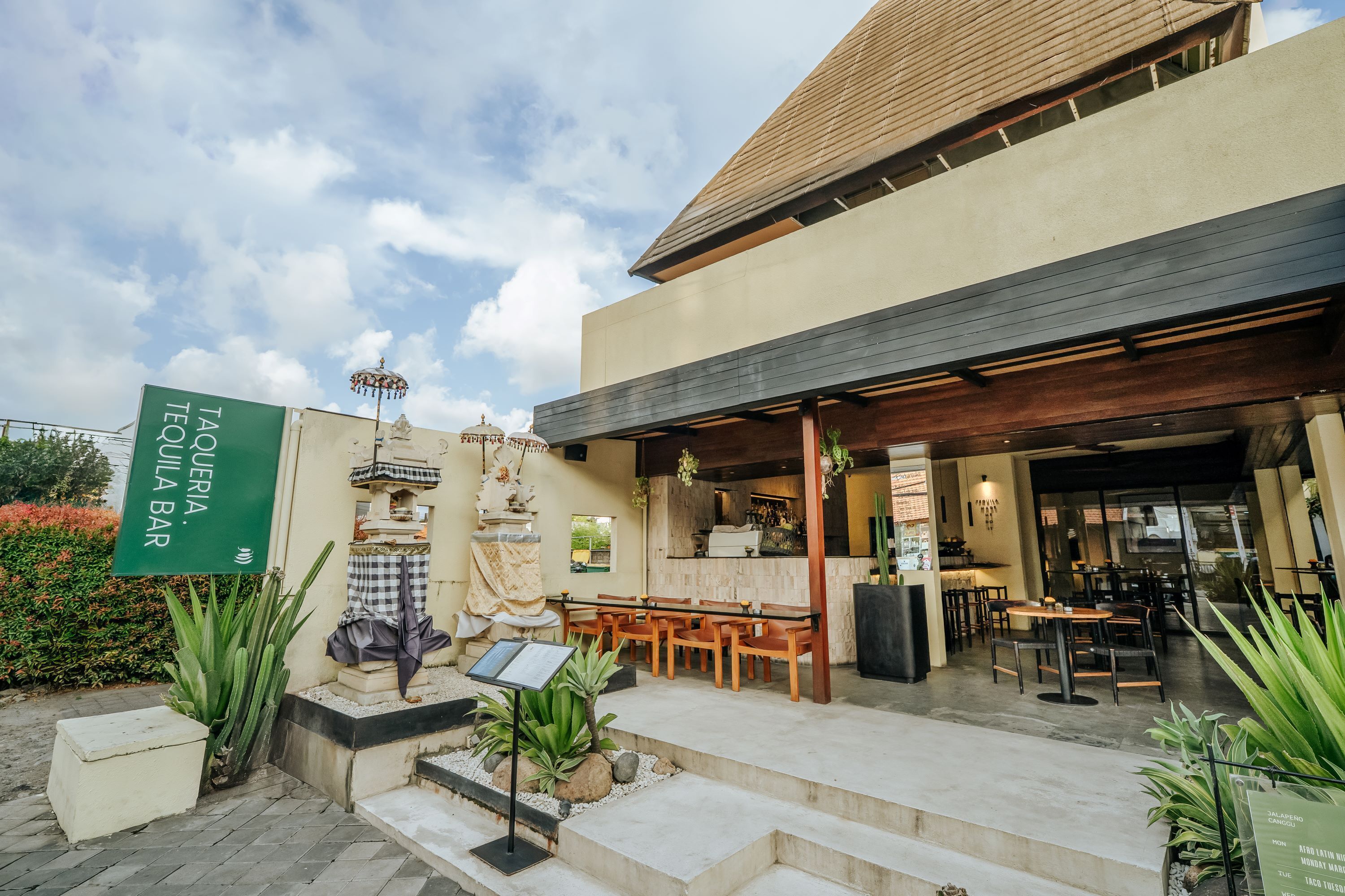 A restaurant with outdoor seating, a sign for 'TAQUERIA TEQUILA BAR', and a decorative fountain.