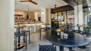 A restaurant with a bar area, multiple seating options including round tables and high stools, and a ceiling fan. - BRAW inn Canggu (Tibubeneng)