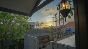 A view from a balcony overlooking a street with buildings, a restaurant, and a sunset. - BRAW inn Canggu (Tibubeneng)