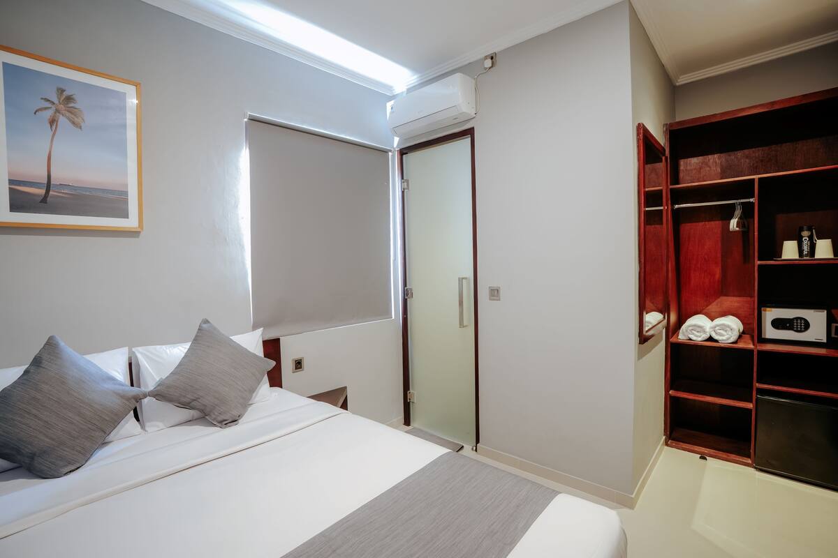 A bedroom with a bed, a wardrobe, a framed picture, and a ceiling light.