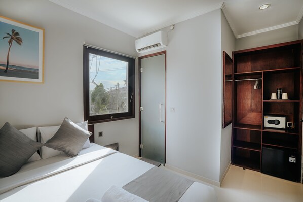Un dormitorio con cama, ventana, puerta y armario empotrado.
