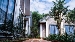 A pathway leading to a building with large windows and a brick facade, surrounded by lush greenery. - Tamcoc Golden Rice (Nam Hoa Lu)