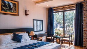 A hotel room with a large bed, a desk, and a view of the outdoors. - Tamcoc Golden Rice (Nam Hoa Lu)