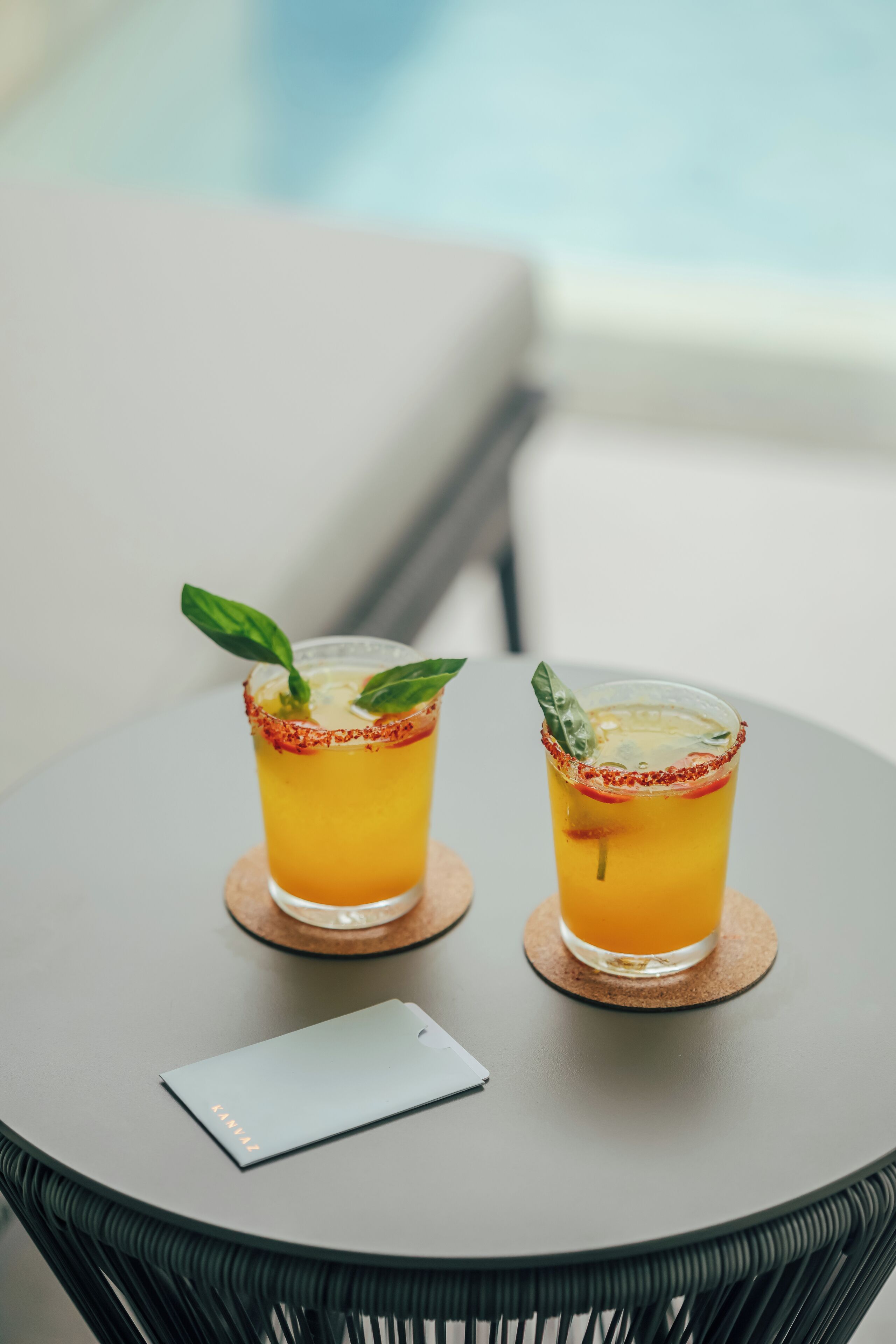 Two glasses of orange beverage on a round table with a smartphone beside them.