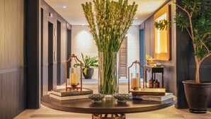 A modern interior with a round table, a decorative vase, and a tall plant. - Kanvaz Village Resort Seminyak (Keroboken Kelod)