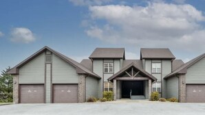 A three-story residential building with a central garage entrance, multiple garage doors, and a symmetrical facade.