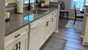 A kitchen with granite countertops, white cabinets, and a wooden floor.