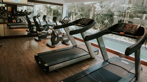 Un gimnasio con cintas de correr, bicicletas estáticas y un espejo grande.