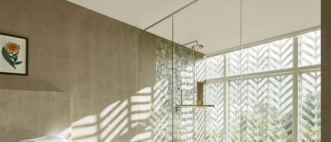 A modern bathroom with a stone wall, a shower with a glass door, and a large window with a geometric pattern.