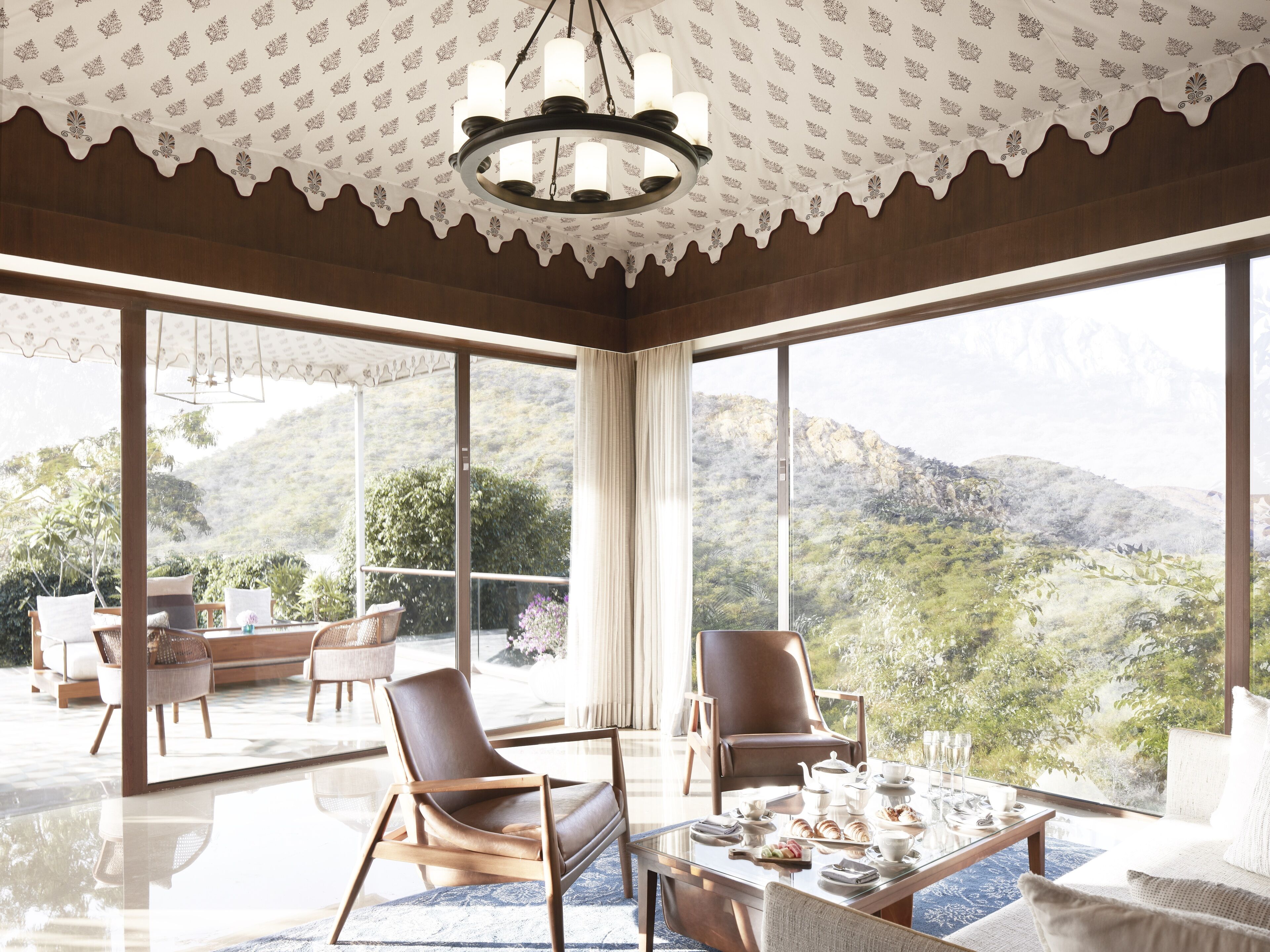 A spacious room with large windows offering a mountain view, a dining area with a table set for two, and modern furniture.