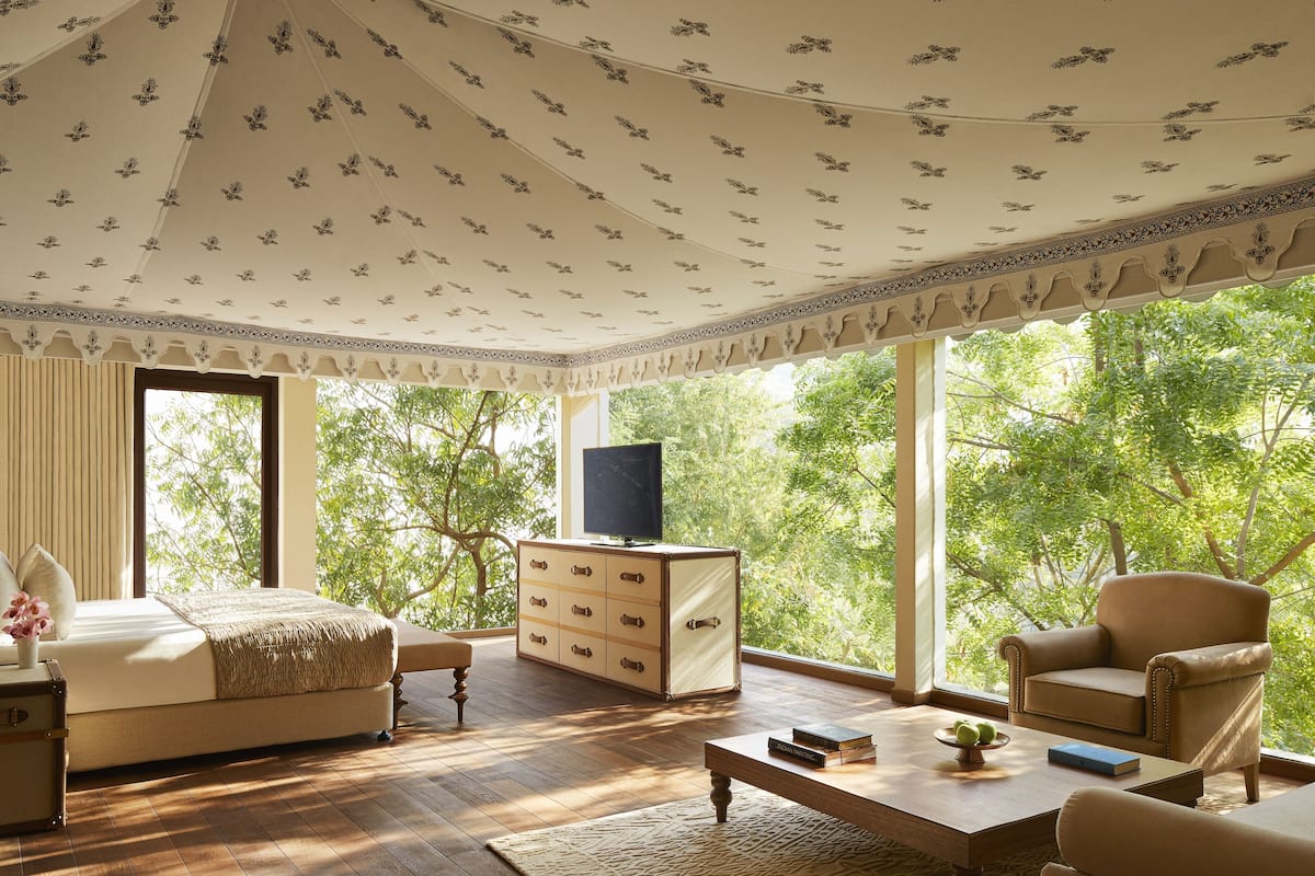 A room with a large window, a bed, a TV, a wooden cabinet, and a sofa.