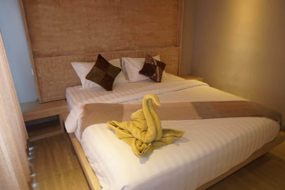 Hotellihuone, jossa on sänky, tyynyjä ja sängylle asetettu pyyhe.