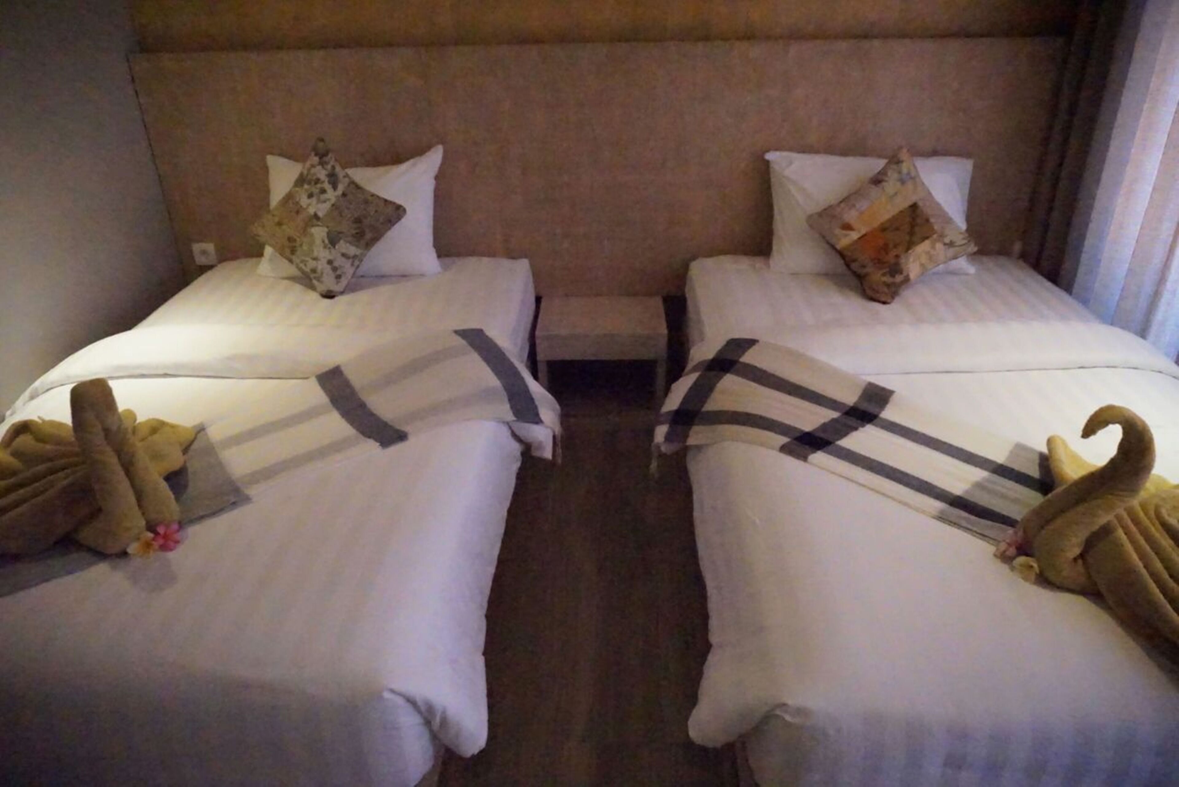 Ein Hotelzimmer mit zwei Betten, jeweils mit Kissen und einem kleinen Nachttisch.