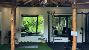 A gym with wooden beams, a hanging dreamcatcher, and exercise equipment. - El Nido Moringa Resort (El Nido)