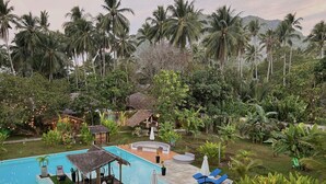 A pool area with lounge chairs and a thatched-roof structure. - El Nido Moringa Resort (El Nido)