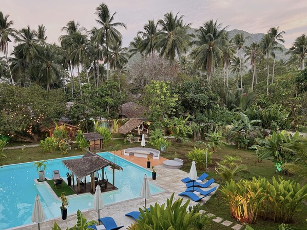 A pool area with lounge chairs and a thatched-roof structure.