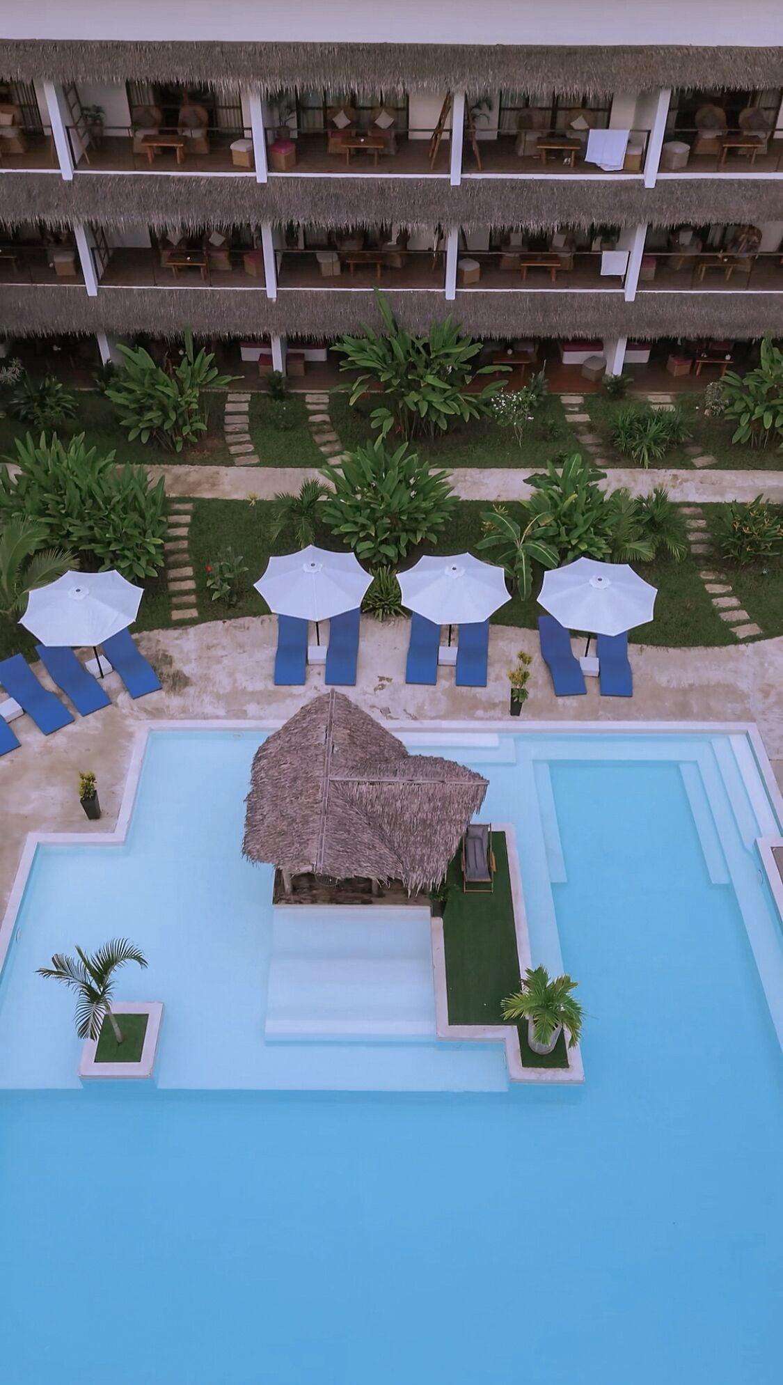 Ein Resort mit Poolbereich, mehreren Liegestühlen und Sonnenschirmen.