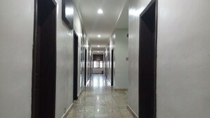 A long, narrow hallway with a polished marble floor, flanked by dark-colored doors on both sides, leading to a bright room at the end. - Dionzec Hotel & Suites (Lagos)
