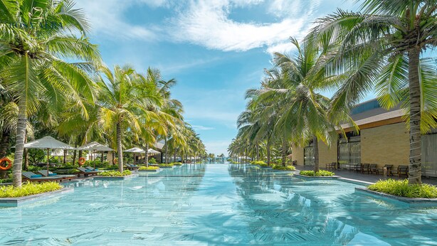 A swimming pool with palm trees and lounge chairs on both sides. - Rosa Alba Resort & Villas Tuy Hoa (Tuy Hoa)