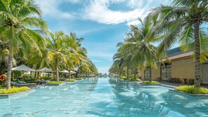 A swimming pool with palm trees and lounge chairs on both sides. - Rosa Alba Resort & Villas Tuy Hoa (Tuy Hoa)