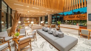 A modern lobby with a large sofa, seating area, wooden slats ceiling, and a reception desk. - Rosa Alba Resort & Villas Tuy Hoa (Tuy Hoa)