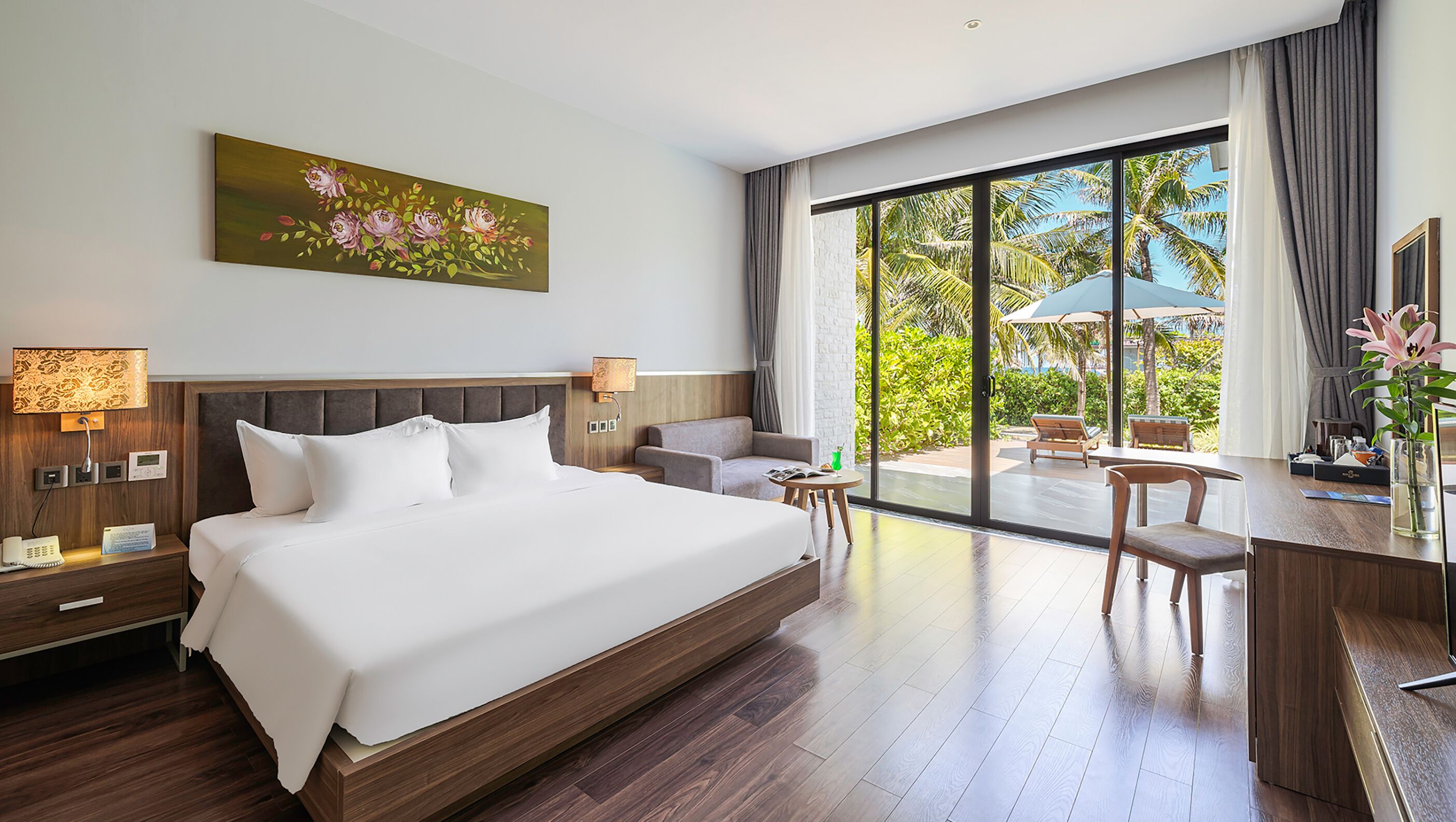 Une chambre d’hôtel avec un grand lit, un bureau, une chaise, une petite table et une vue sur l’extérieur.