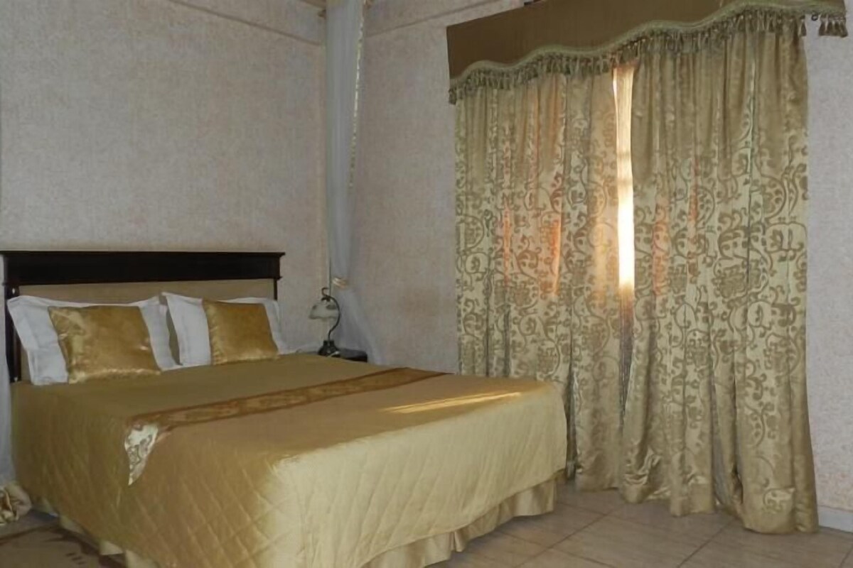 A hotel room with a large bed, a nightstand, and a lamp.