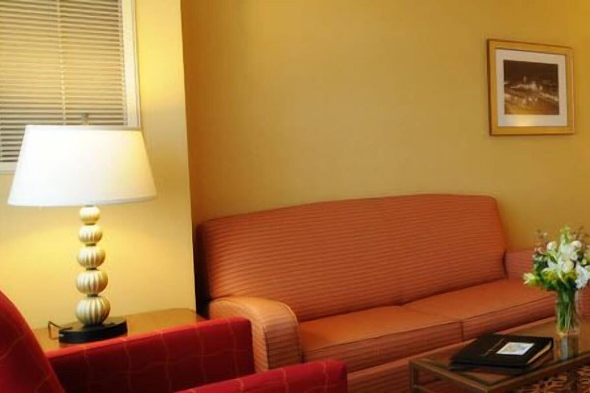 A hotel room with a bed, a sofa, a nightstand, and two lamps.