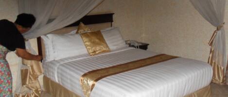 A bed with a canopy, a bedside table, and a telephone.