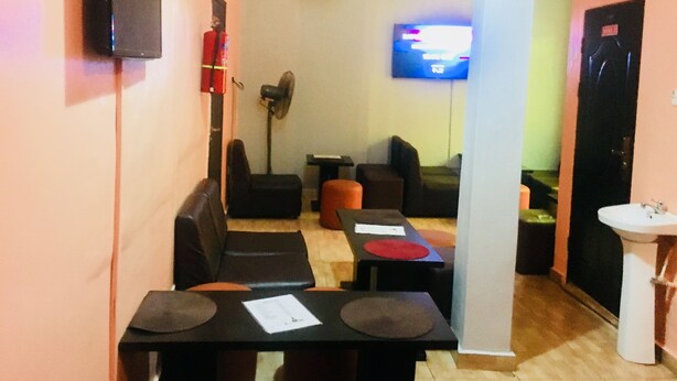 A hotel room with a seating area, a television, a fan, and a sink. - Esporta Hotel Yaba (Lagos)