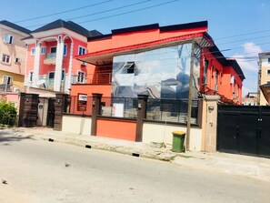 Stunning red facade building with a large glass window and gated entrance.