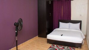 A bedroom with a bed, a microphone stand, an air conditioning unit, and a wardrobe. - Esporta Hotel Yaba (Lagos)
