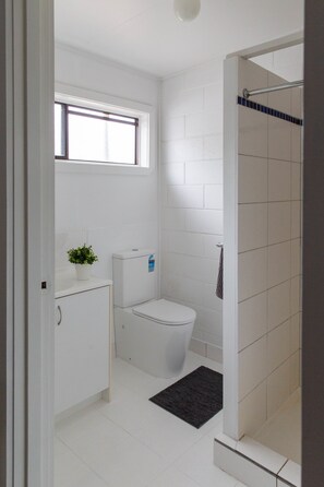 A small, clean bathroom with a toilet, a sink, and a shower.