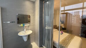 A modern hotel room with a large bed, a glass partition, a bathroom with a sink and mirror, and a city view. - Cherry Inn (Magong)