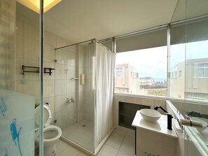 Habitación doble, vista parcial al océano | Baño | Regadera, secadora de cabello, pantuflas 