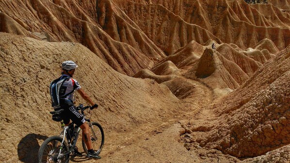 Um ciclista de montanha numa trilha com terreno acidentado e irregular.