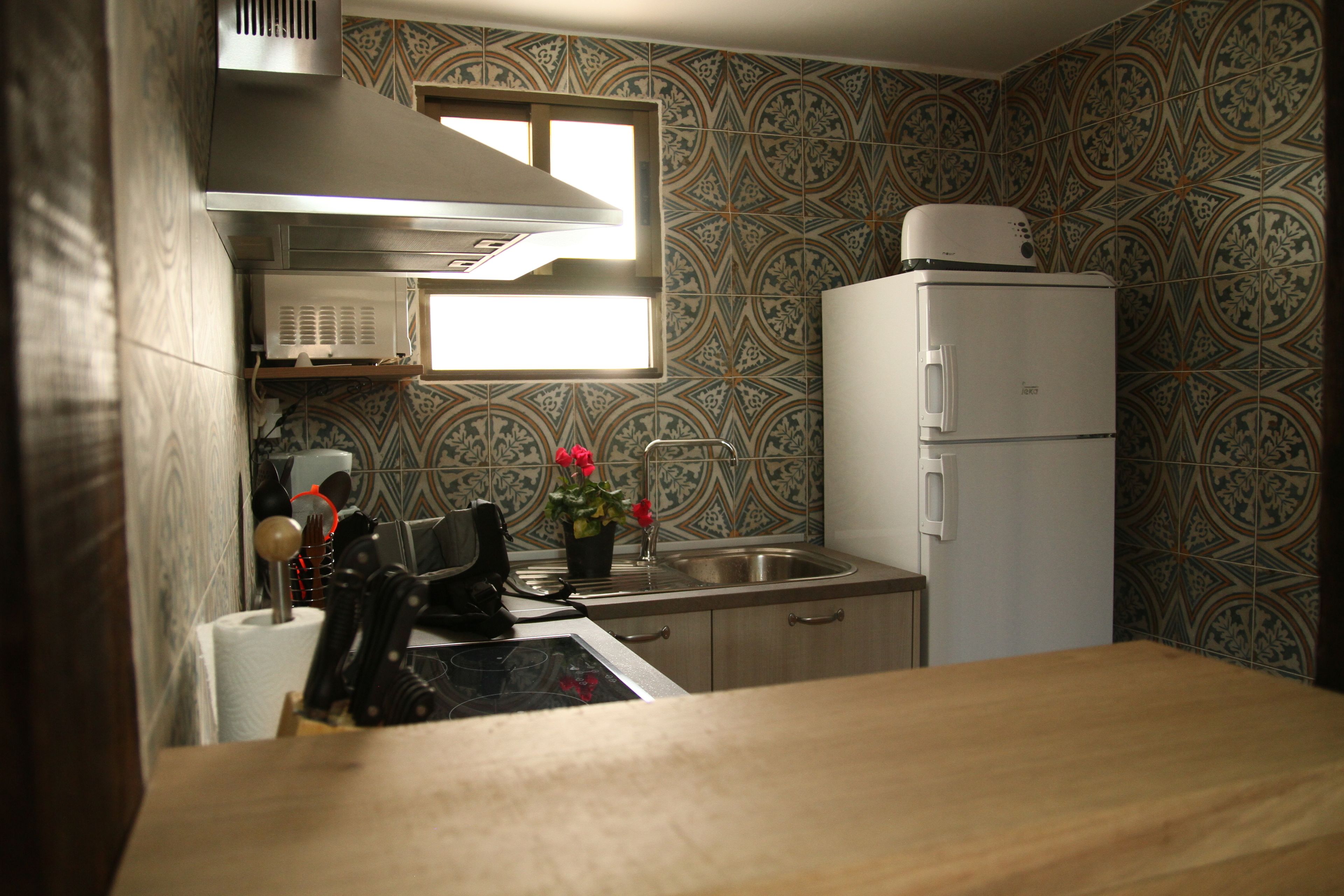 A compact kitchen with a microwave, refrigerator, and a window above the sink.
