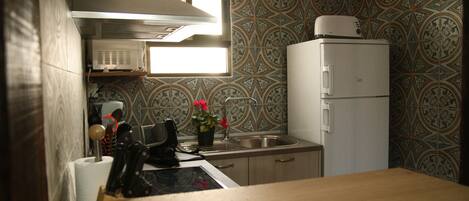 A compact kitchen with a microwave, refrigerator, and a window above the sink.