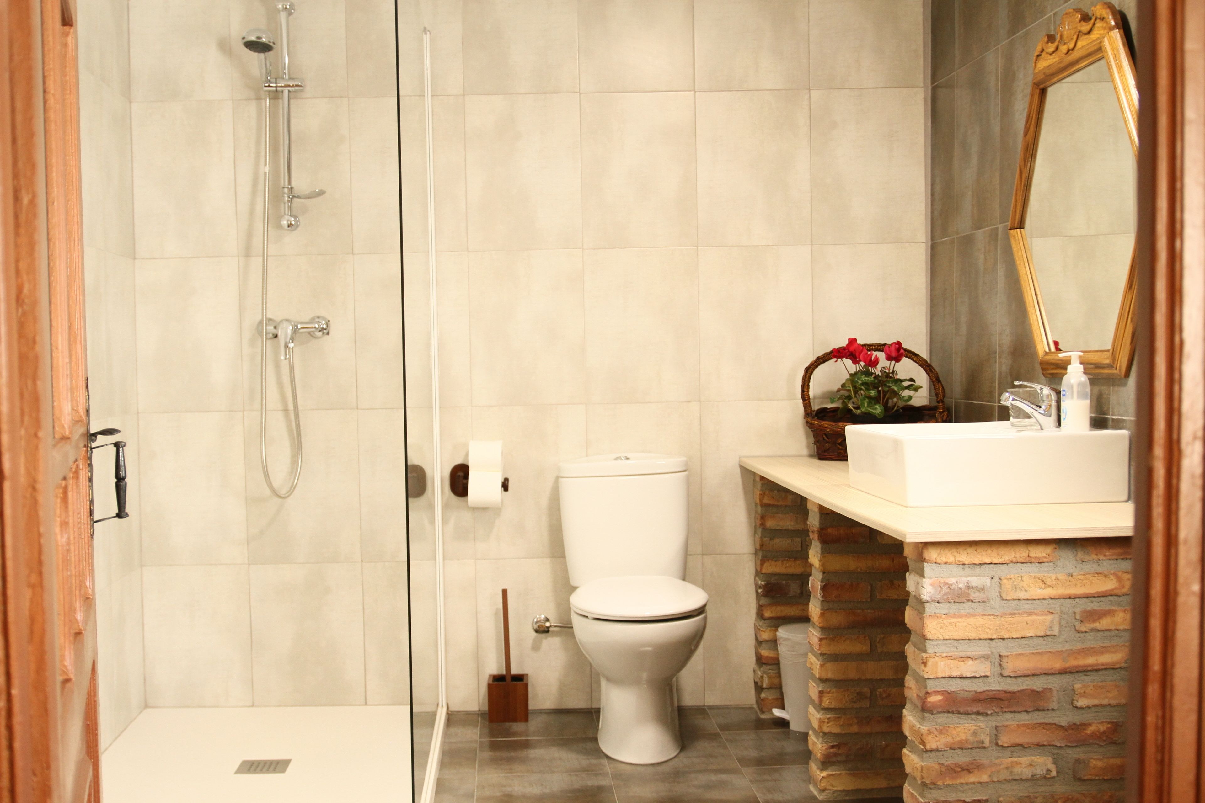Une salle de bain équipée d’une douche, de toilettes, d’un lavabo et d’un miroir.